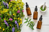 herbs and flowers next to essential oil bottles