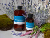 Two bottles of Brine & Bloom Fragrance2U fragrance oil with lavender flowers and moss in the background