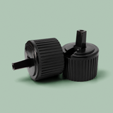 Two black plastic bottle caps with ribbed flanges and threaded necks, shown on a solid sage green background.