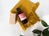Bottle of Neroli & Peppercorn Fragrance2U fragrance oil with a bar of soap and a yellow towel on a white background