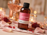 Bottle of Pomegranate Rose Fizz Fragrance2U fragrance oil with a glass of pink champagne on a decorative table.