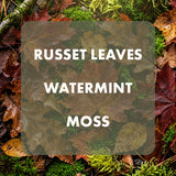 A square product label or swatch card with rounded corners over a natural forest floor background. The card is semi-transparent and reads 'RUSSET LEAVES WATERMINT MOSS' in white uppercase text.