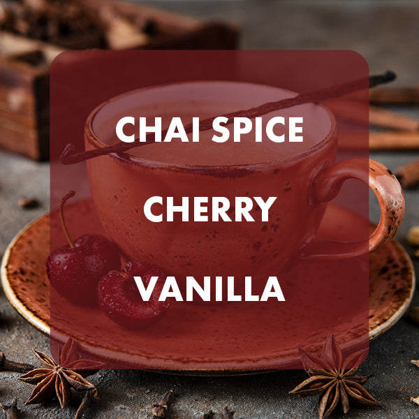 A cup of chai spice latte with cherry pieces and vanilla bean visible, overlaid with a large translucent red label reading 'CHAI SPICE CHERRY VANILLA' on a rustic tabletop with cinnamon sticks and star anise.