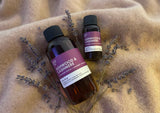 Two bottles of Ashwood & Cashmere Fragrance2U fragrance oil on a textured fabric background with lavender sprigs.