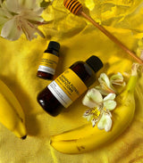 Two bottles of banana flower & honeycomb on a yellow fabric background with bananas and flowers.