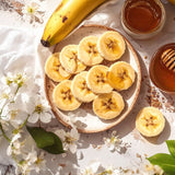 Sliced bananas on a plate with flowers and honey on a light background