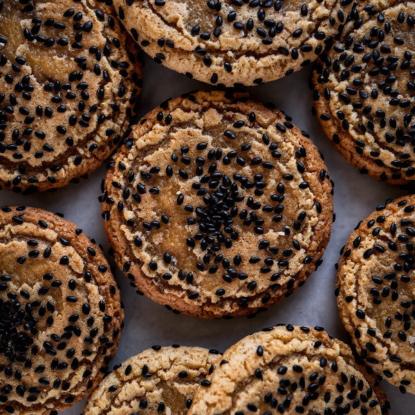 Cookies with black sesame seeds arranged on a white surface