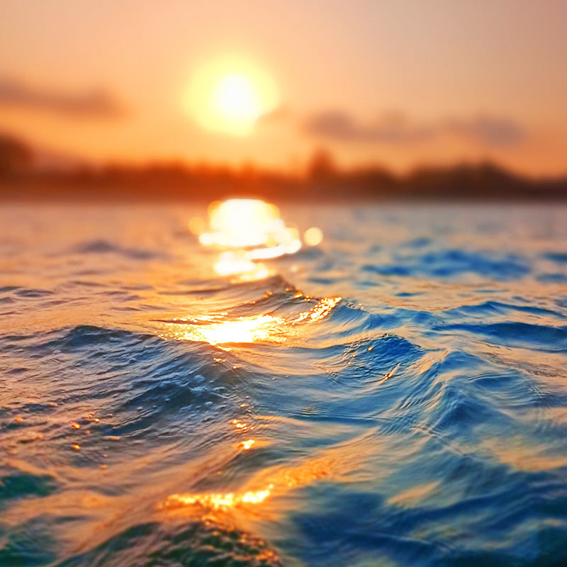 sun shining over ocean water at sunset