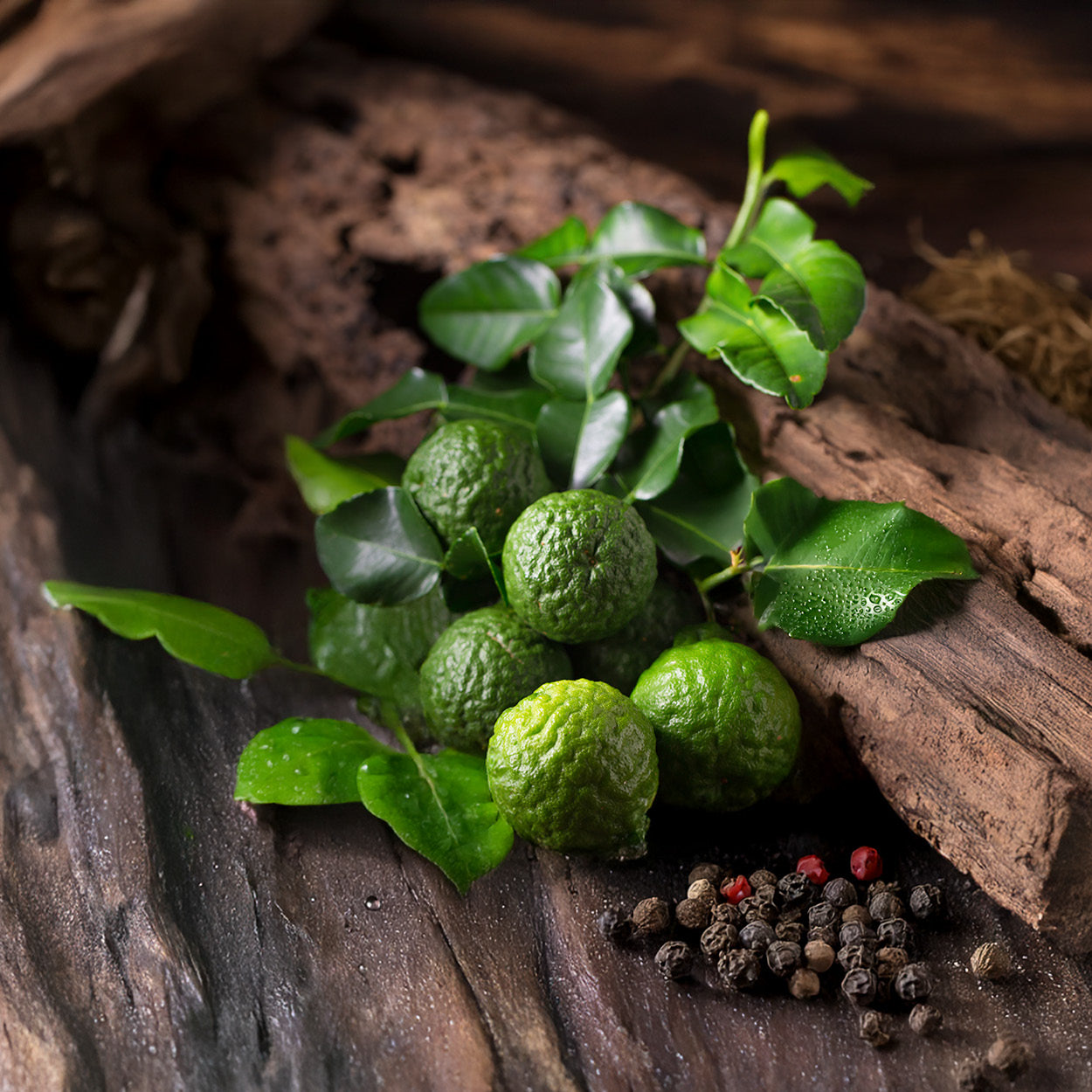 bergamot with leaves and peppercorns on a wooden surface