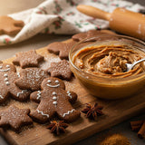 Gingerbread cookies on a wooden board with a bowl of gingerbread spread.