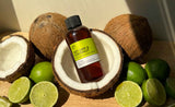 bottle of Fragrance2U Key Lime & Coconut fragrance oil sitting in a coconut with limes nearbu