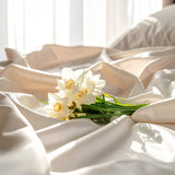 white flowers laying on a bed with silky sheets