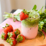 Glass of iced green tea with strawberry on a wooden surface
