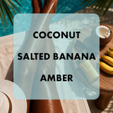A lifestyle image featuring a person's legs in a pool area with a large semi-transparent text overlay reading 'COCONUT SALTED BANANA AMBER'. Surrounding props include a wooden tray with a coconut, bananas, tanning lotion, and sunglasses.