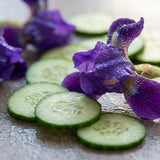 Sliced cucumbers on a textured surface with purple flowers.